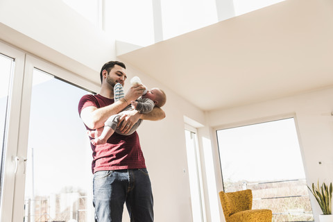 Vater füttert seinen kleinen Sohn mit der Flasche, lizenzfreies Stockfoto