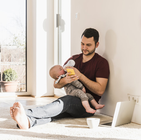 Vater füttert seinen kleinen Sohn mit der Flasche, lizenzfreies Stockfoto