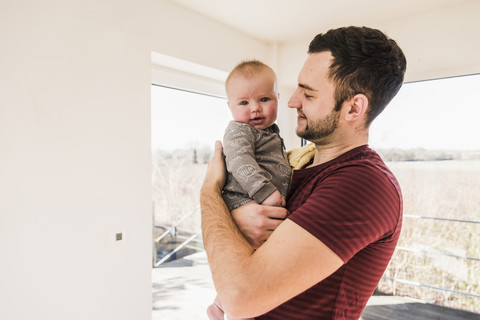 Vater hält seinen kleinen Sohn in seinen Armen, lizenzfreies Stockfoto