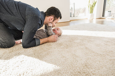 Vater und kleiner Sohn spielen auf dem Teppich zu Hause - UUF09898