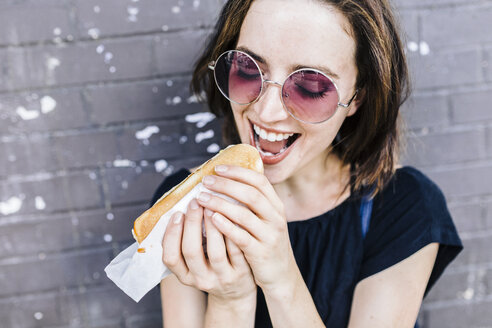 Porträt einer Frau, die einen Hot Dog isst - GIOF01869