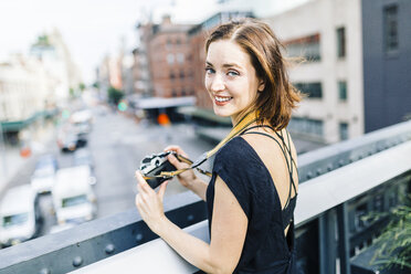 USA, New York City, lächelnde Frau mit Kamera auf der High Line in Manhattan - GIOF01874
