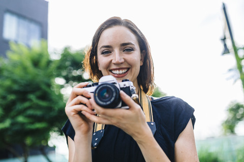 Porträt einer lächelnden Frau mit Kamera, lizenzfreies Stockfoto