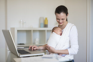 Mother with baby girl in sling working from home - DIGF01508