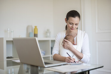 Mutter mit Baby im Tragetuch arbeitet von zu Hause aus - DIGF01509