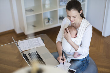 Mutter mit Baby im Tragetuch arbeitet von zu Hause aus - DIGF01513