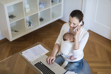 Mutter mit Baby im Tragetuch arbeitet von zu Hause aus - DIGF01515