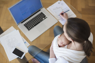 Mother with baby girl in sling working from home - DIGF01516