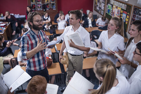 Drama teacher leading students holding booklets - ZEF12812