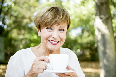 Porträt einer lächelnden älteren Frau, die im Freien eine Tasse Kaffee trinkt - WESTF22682