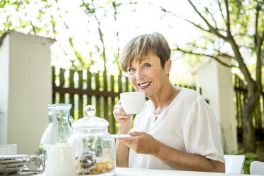 Porträt einer lächelnden älteren Frau, die im Freien eine Tasse Kaffee trinkt - WESTF22686