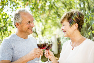 Smiling senior couple clinking red wine glasses outdoors - WESTF22690