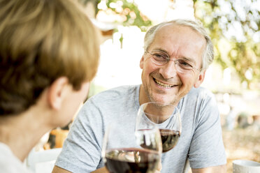Smiling senior couple clinking red wine glasses outdoors - WESTF22697