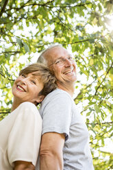 Porträt eines glücklichen älteren Paares Rücken an Rücken im Freien - WESTF22712