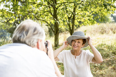 Älterer Mann fotografiert seine Frau auf einer Wiese - WESTF22724