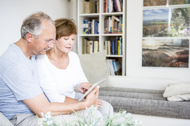 Älteres Paar sitzt zu Hause auf der Couch und benutzt ein digitales Tablet - WESTF22730