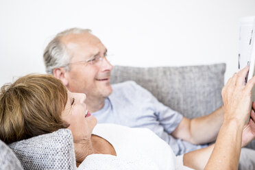 Älteres Ehepaar zu Hause auf der Couch liegend mit digitalem Tablet - WESTF22731