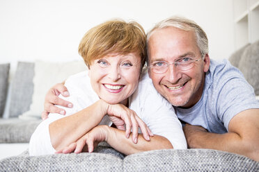 Porträt eines lächelnden älteren Paares zu Hause auf der Couch liegend - WESTF22748