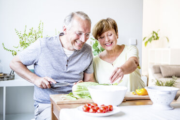 Happy senior couple in kitchen preparing salad together - WESTF22755