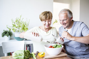 Glückliches älteres Paar in der Küche bei der Zubereitung von Salat - WESTF22758