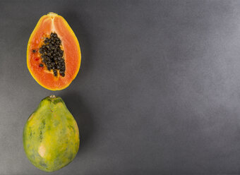 Ganze und eine halbe Papaya auf grauem Grund - JUNF00841