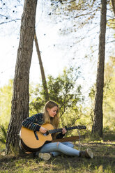 Young woman playing guitar in nature - KKAF00414