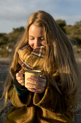 Lächelnde junge Frau mit heißem Getränk in der Natur - KKAF00424