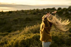 Young woman standing in nature raising her arms - KKAF00425