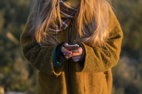 Junge Frau hält Mobiltelefon im Freien - KKAF00433