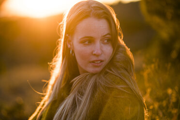 Young woman in nature at sunset turning around - KKAF00441