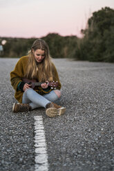 Junge Frau spielt Ukulele auf einer Straße - KKAF00446