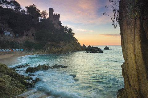 Spanien, Costa Brava, Lloret de Mar, Blick vom Strand zum Castillo de los Plaja bei Sonnenaufgang, lizenzfreies Stockfoto