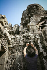 Kambodscha, Angkor Wat, Angkor Thom, Bayon-Tempel, Tourist nimmt Handy-Foto - REAF00206