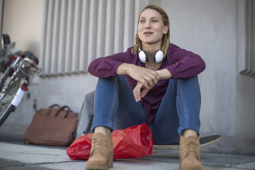 Junge Frau sitzt auf einem Skateboard auf der Straße - ZEF12839