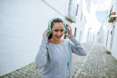 Junge Frau trägt Kopfhörer beim Training - KIJF01227