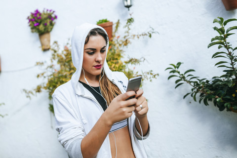 Junge Frau trägt Kopfhörer und schreibt eine Textnachricht, lizenzfreies Stockfoto