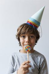 Portrait of little boy with lollipop and four party hats on his head - VABF01149