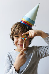 Porträt eines glücklichen kleinen Jungen mit Lutscher und vier Partyhüten auf dem Kopf - VABF01150