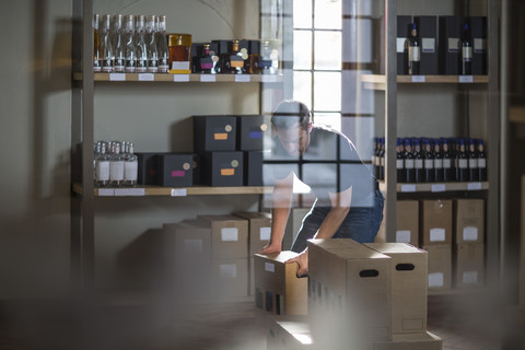 Mann verpackt Weinflaschen in einem Geschäft, lizenzfreies Stockfoto