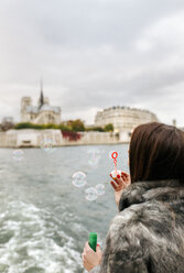 Paris, France, tourist taking a cruise on Seine River and blowing soap bubbles - MGOF02997
