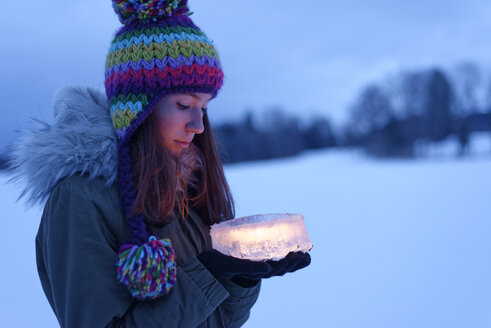 Teenage girl holding cake made of ice with candle inside - LBF01566