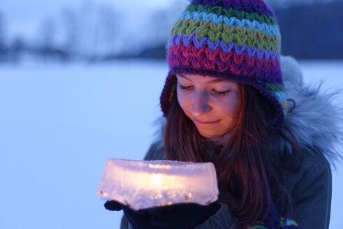 Smiling teenage girl holding cake made of ice with candle inside - LBF01567