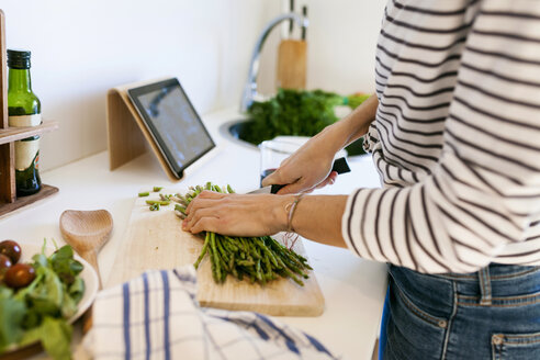 Young woman cooking at home using digital tablet for recipe - VABF01166