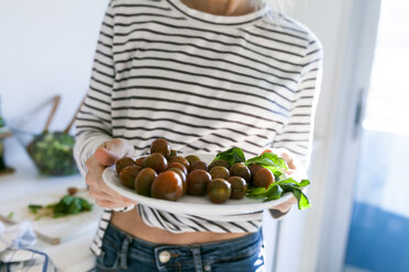 Young woman holding plate of cherry tomatoes - VABF01172