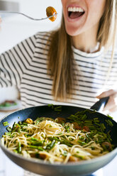 Young woman holding pan with vegan pasta dish - VABF01183