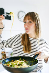 Young woman holding pan with vegan pasta dish - VABF01184