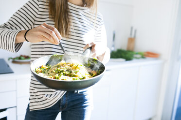 Junge Frau hält Pfanne mit veganem Nudelgericht - VABF01185