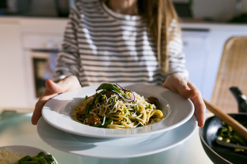 Young woman serving vegan pasta dish stock photo