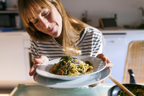 Young woman serving vegan pasta dish stock photo