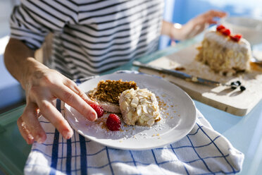 Junge Frau, die ein Stück veganen Kuchen garniert - VABF01197